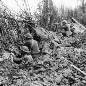 Soldiers of the 33rd Infantry Division hiding behind German camouflage.