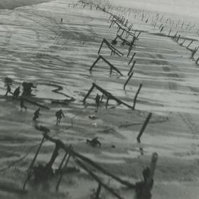 Allied reconnaissance of German soldiers setting up beach obstacles.