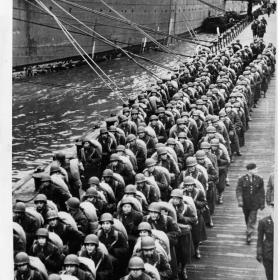With full packs, an American quartermaster battalion line an English pier waiting to board a transport for shipment to a new station.