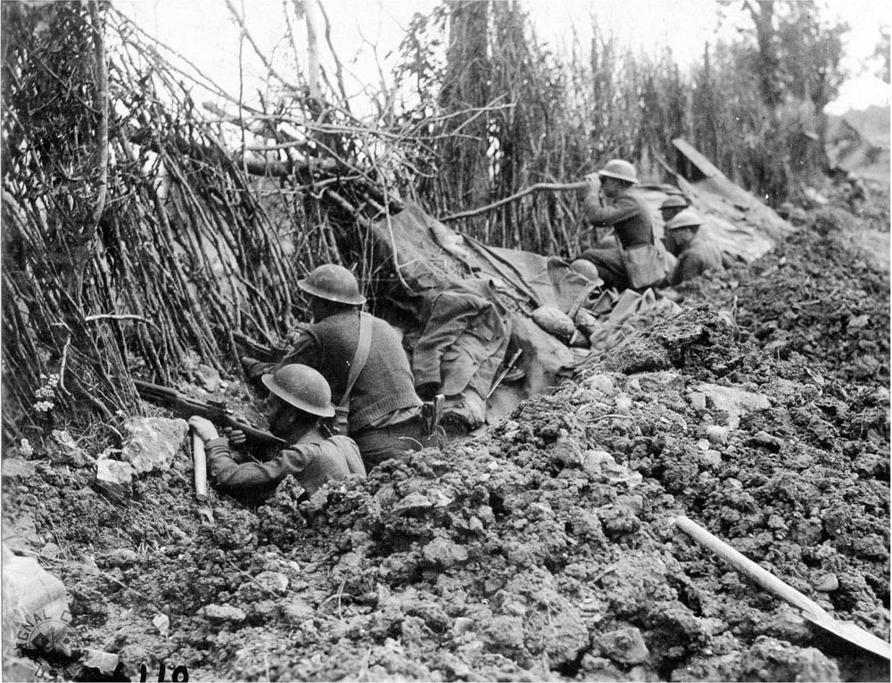 Soldiers of the 33rd Infantry Division hiding behind German camouflage.