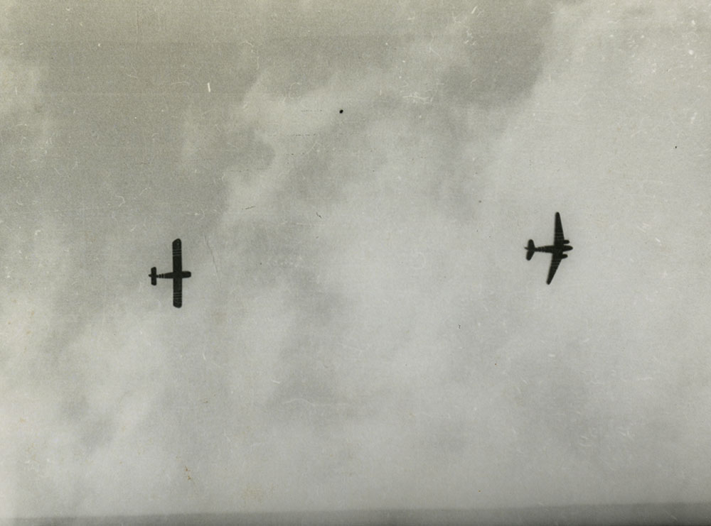 View looking up to C-47 pulling glider across sky.