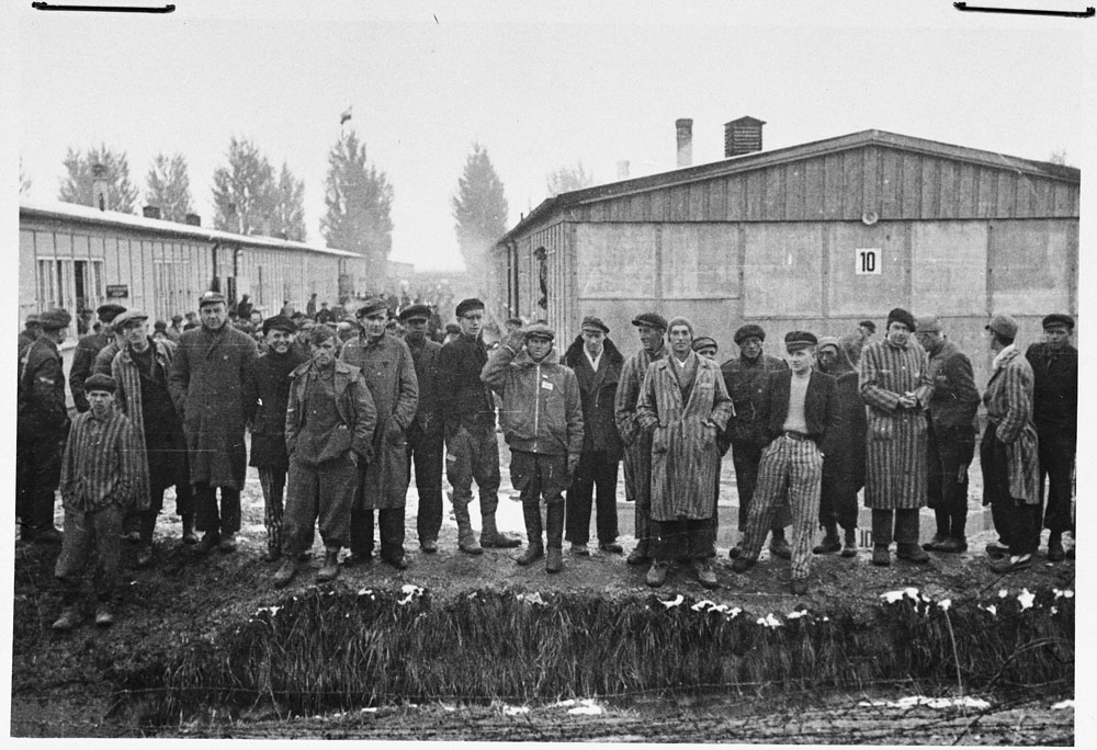 Group of survivors standing by the moat at Dachau concentration camp.