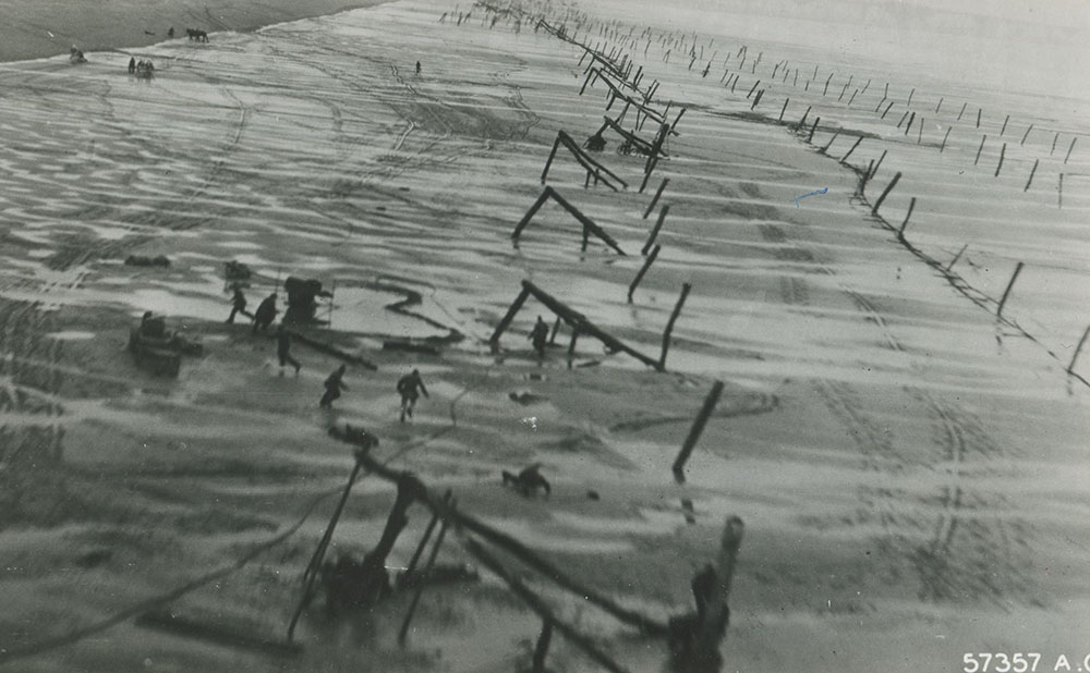 Allied reconnaissance of German soldiers setting up beach obstacles.