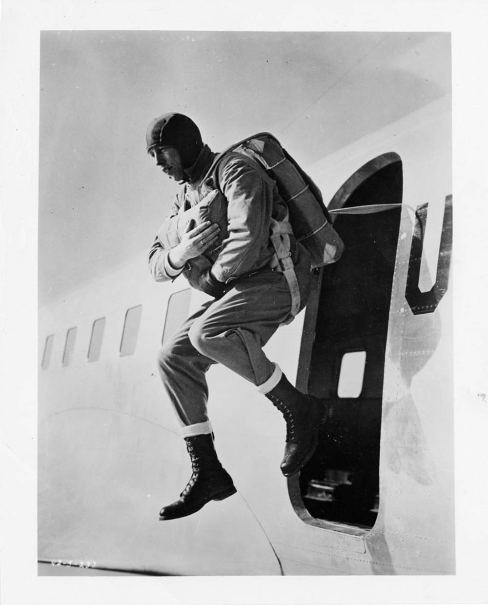 Photograph shows soldier demonstrating a jump from a plane.
