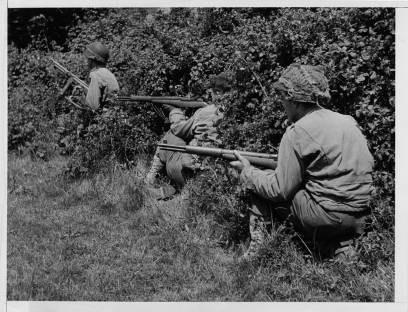 Taking cover in the bushes this allied sniper patrol searches nearby trees and shrubs for any enemy soldiers waiting to ambush them.