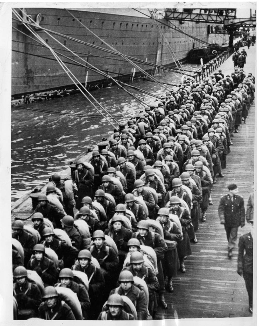 With full packs, an American quartermaster battalion line an English pier waiting to board a transport for shipment to a new station.