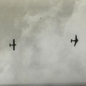 View looking up to C-47 pulling glider across sky.