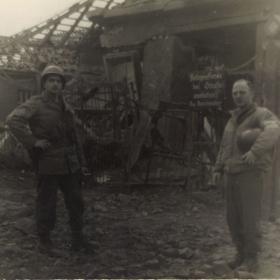 Two American soldiers stand near the entrance sign to Dora-Mittelbau concentration camp.
