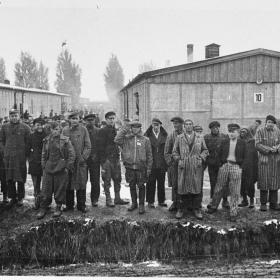 Group of survivors standing by the moat at Dachau concentration camp. 