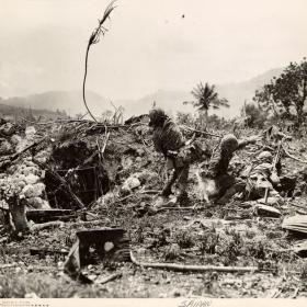 Marines throwing grenades on Saipan under enemy fire from Japanese forces.