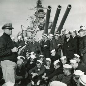 Aboard USS Nevada, a naval officer reads a letter from the Western Naval Task Force commander, Admiral Alan Kirk, describing when and where the naval bombardment will occur.