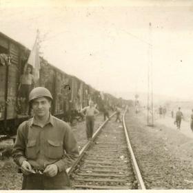 American soldier stands next to a trainload of Buchenwald survivors, on their way to a displaced persons camp. 
