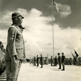 American flag is risen while Japanese sailors watch.