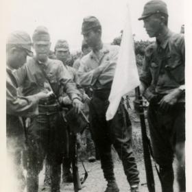 Surrendering Japanese soldiers carrying a white flag.