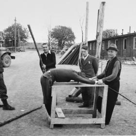 Ohrdruf camp survivors reenact torture scenes to liberators. 