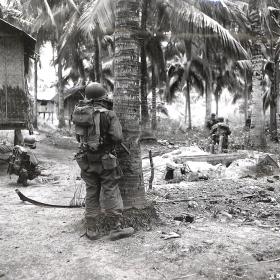 Soldiers making way through village on Luzon, Philippines.