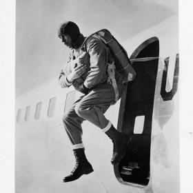 Photograph shows soldier demonstrating a jump from a plane.