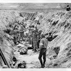 Somewhere in the beachhead area, American medical corpsmen convert a German anti-tank ditch into a temporary first aid station. Originally intended as invasion defenses, the ditches proved adequate for their improvised use.