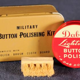 There is also a small hard-bristled brush made of wood, a polishing cloth, and a black plastic guard that would be inserted behind and around the button in order to protect the uniform.